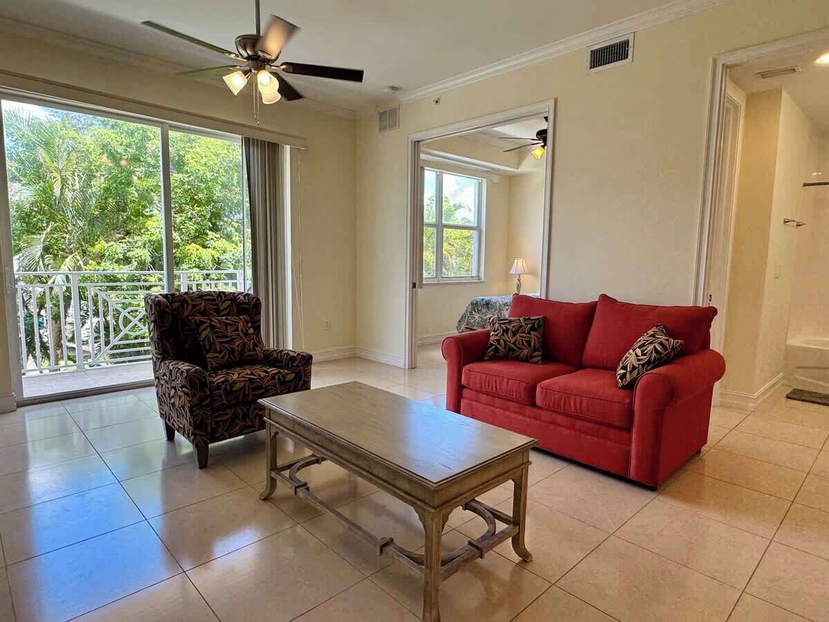 A spacious living room with a red sofa, patterned armchair, and a wooden coffee table.