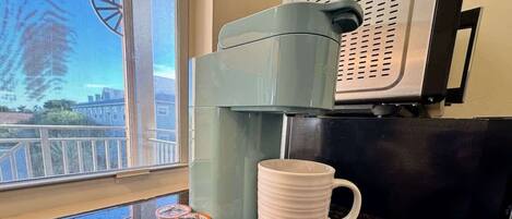 A coffee machine with a milk frother and a stack of disposable cups on a kitchen counter.