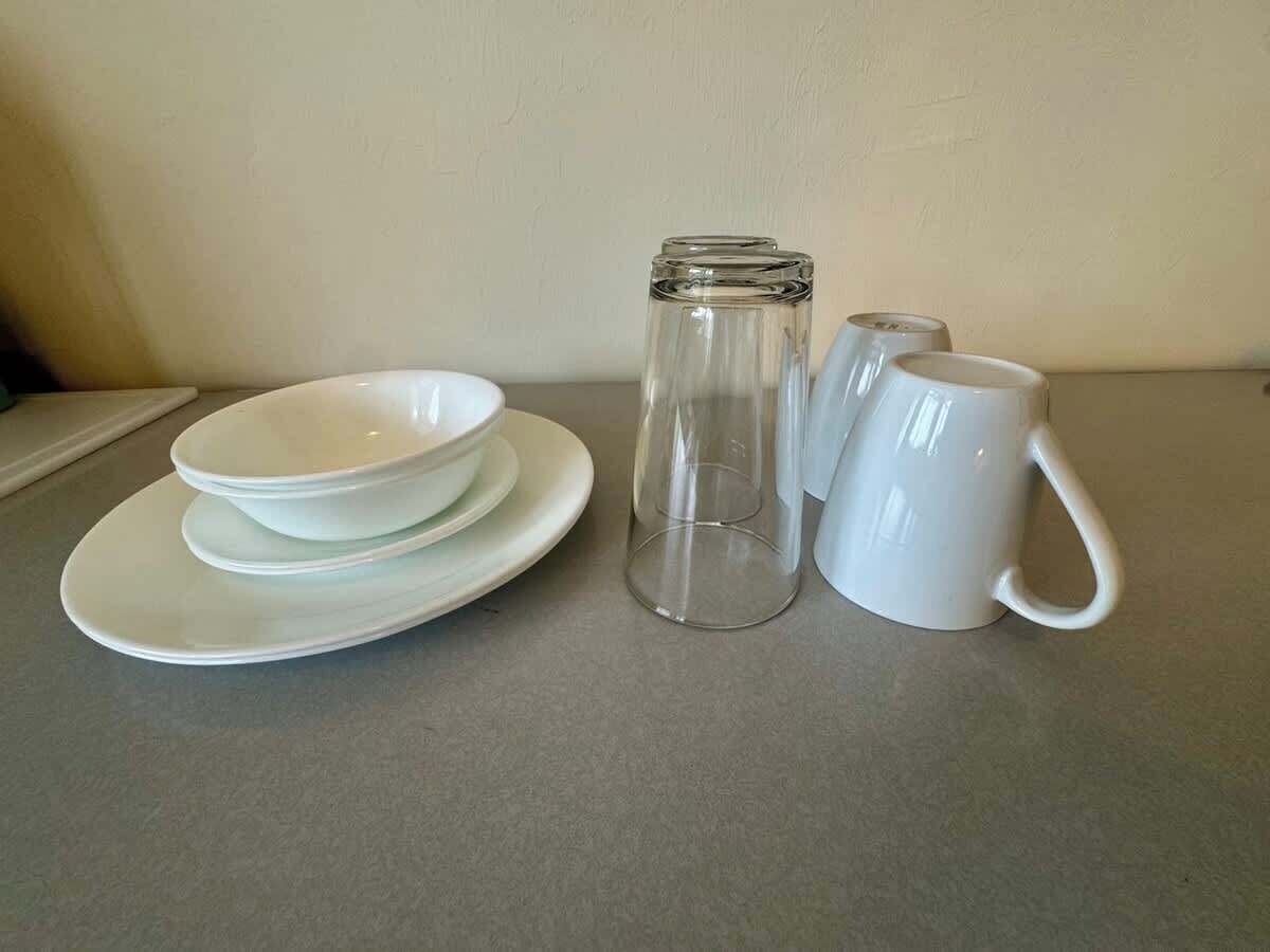 A set of white dishes and a mug on a grey countertop.