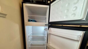 Avoin jääkaappi, jossa on useita hyllyjä ja erillinen pakastinosa.