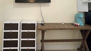 A room with a mounted TV, two white storage units with brown handles, a wooden desk, and a coffee machine. - Bright Studio – Free WiFi – Bonita Springs (Bonita Springs)