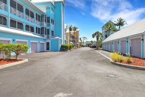 A street view of a residential area with multi-story buildings, each with a garage door and a balcony. - Modern Retreat – Beach Gear – Near the Sand (Bonita Springs)