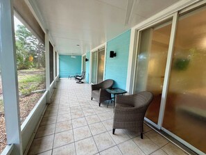 A covered outdoor area with a tiled floor, a table, two chairs, and a ceiling fan. - Modern Retreat – Beach Gear – Near the Sand (Bonita Springs)