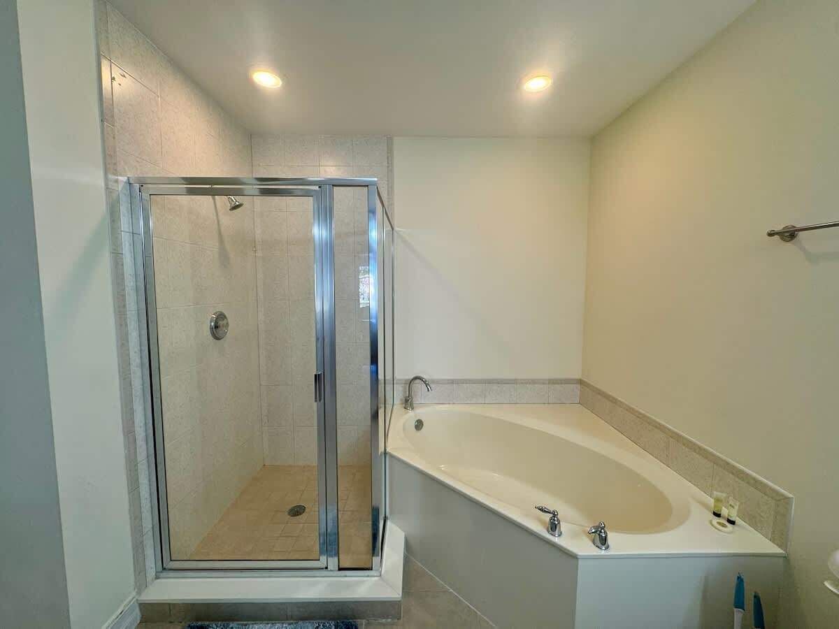 Un baño moderno con ducha de vidrio, bañera independiente y tocador con espejo.