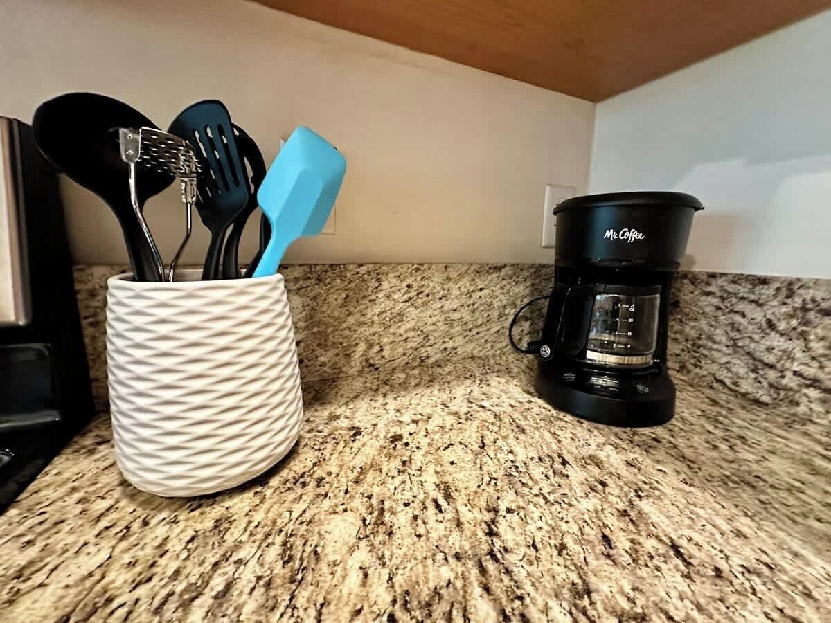 Een keukentafel met een koffiezetapparaat en een houder voor keukengerei.