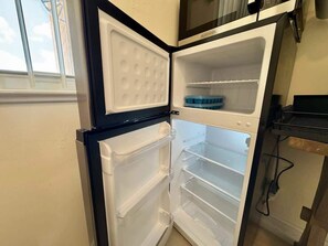 Eine Küche mit Einbaukühlschrank, Fenster und Mikrowelle.