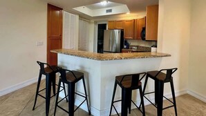 A kitchen with a central island, bar stools, wooden cabinets, and stainless steel appliances. - Sunlit Getaway – Free WiFi – 1 Mi to the Gulf (Bonita Springs)