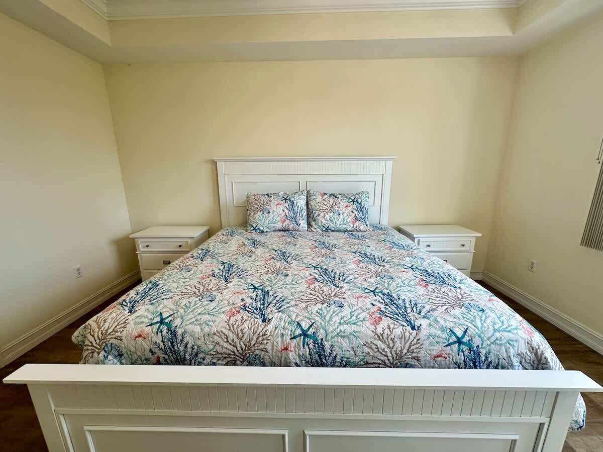 Een slaapkamer met een bed, twee nachtkastjes en een hoofdeinde.