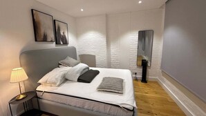 A modern bedroom with a bed, bedside lamp, and artwork on the wall. - Citylink Central Flat 1 (London)