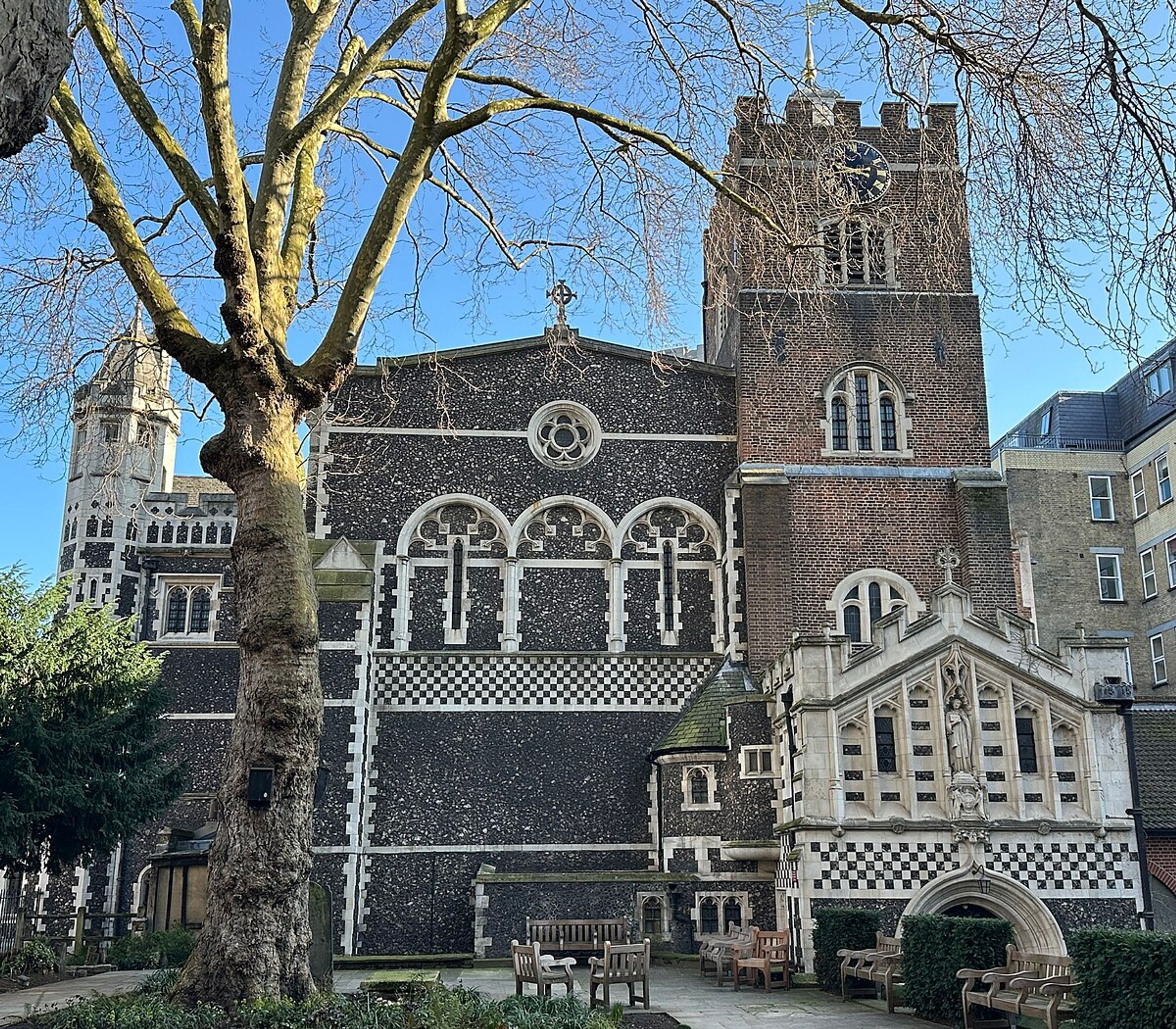 A historic building with a prominent clock tower, arched windows, and a checkered pattern on the facade.