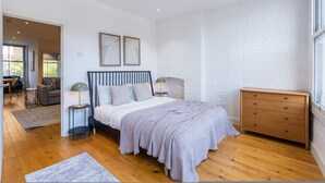 A bedroom with a bed, bedside tables, a dresser, and a window. - Citylink Central Flat 2 (London)