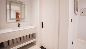 A modern bathroom with a white vanity, a large mirror, and a door. - 2-bedroom apartment in beautiful Riyadh with Full Facilities (Riyadh)