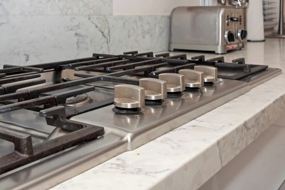 A kitchen with a stainless steel stove, a toaster, and a marble countertop.