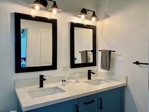 A bathroom with two sinks, black-framed mirrors, and a towel rack. - Comfy house in Potrero, next to pool, 2 bed/ 2 bath, close to town and beaches! (Potrero)