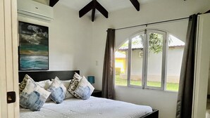 Um quarto com uma cama, um quadro na parede e uma janela com cortinas.