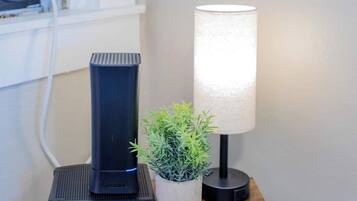 A black ARRIS Spectrum device on a wooden surface, a white lamp, and a small potted plant.