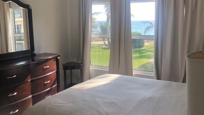 A hotel room with a bed, a dresser, a mirror, and a view of the ocean. - Sub tropical paradise (Hillsboro Beach)