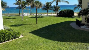 A well-maintained lawn with palm trees, a pathway, and a view of the ocean. - Sub tropical paradise (Hillsboro Beach)
