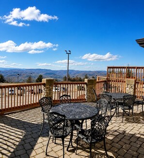 A patio with outdoor seating, a stone wall, and a view of mountains.