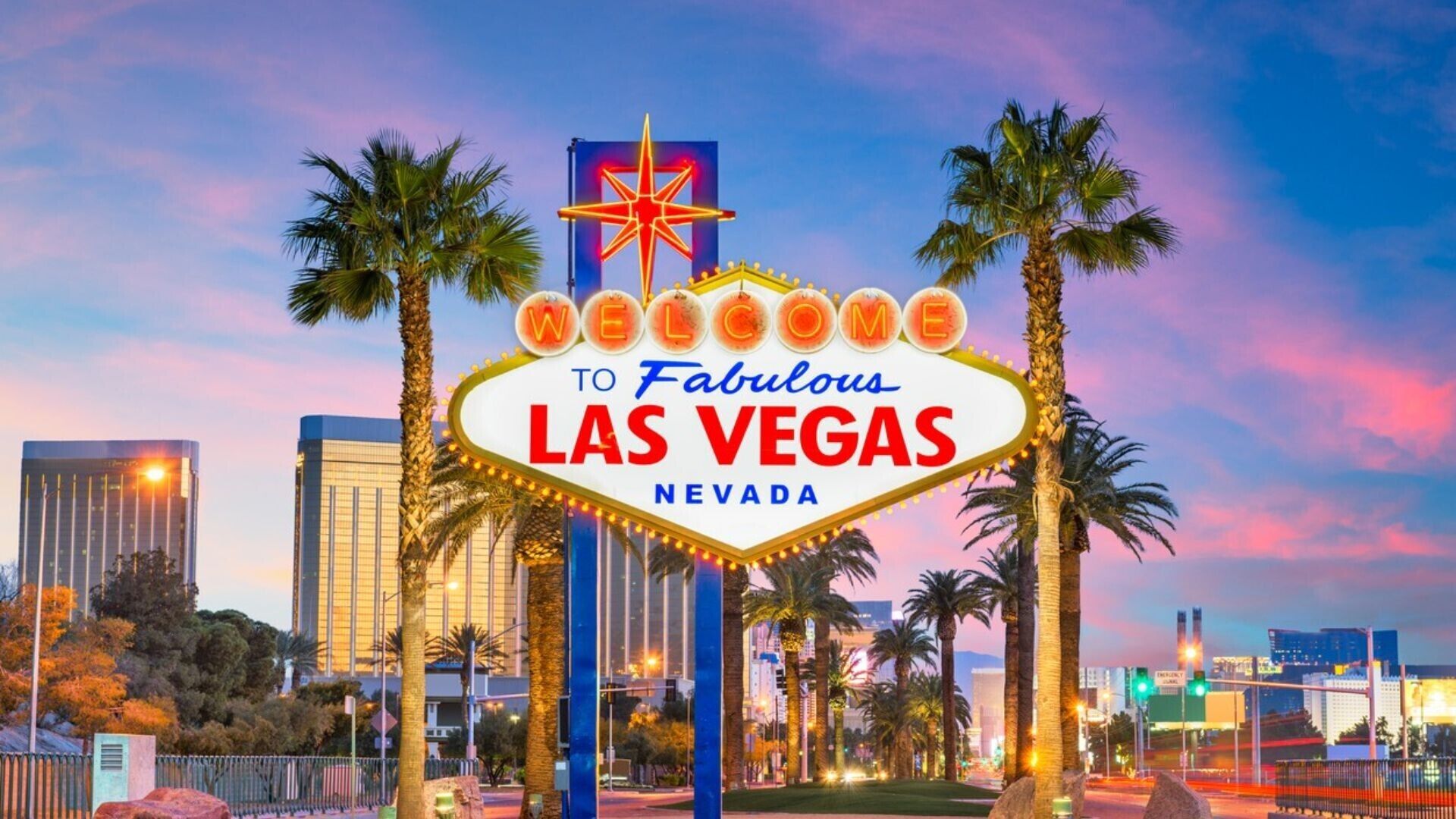 The iconic Las Vegas sign with palm trees and city skyline in the background.