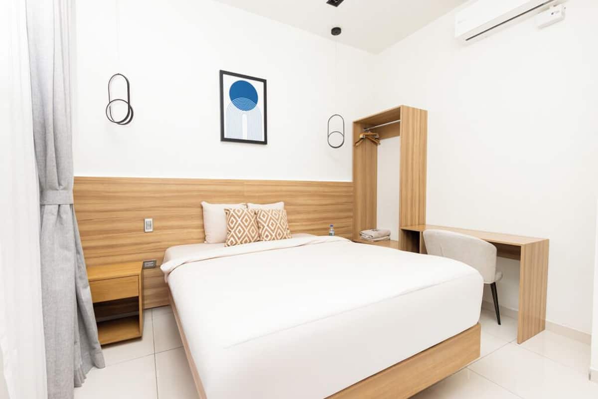 Una habitación de hotel moderna con una cama grande, un escritorio y un armario.