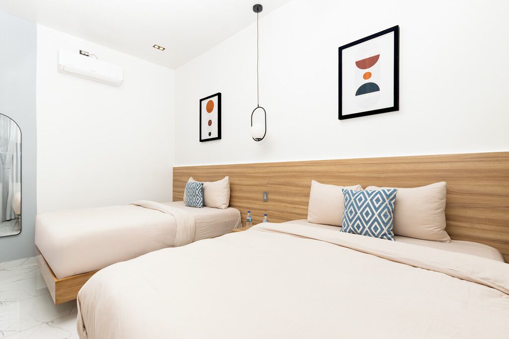 Een moderne hotelkamer met twee bedden, een houten hoofdbord en een minimalistische inrichting.