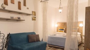 Une pièce avec un canapé bleu, un lit à baldaquin, un globe terrestre sur une étagère et une pancarte « Bienvenue ».