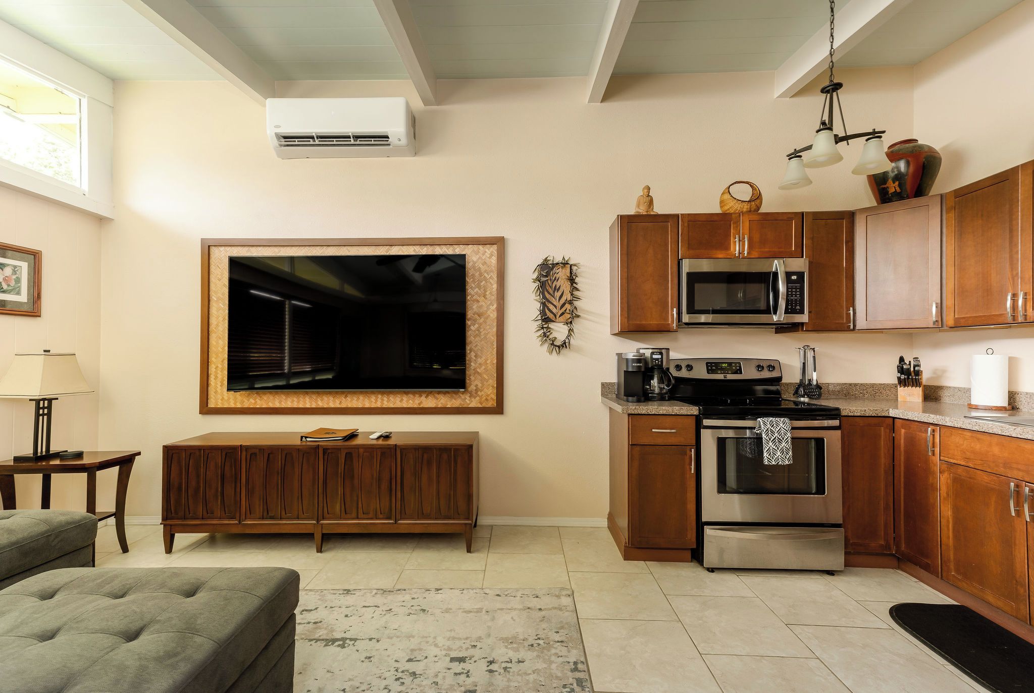 Una cocina moderna con armarios de madera, electrodomésticos de acero inoxidable y un televisor de pantalla plana grande montado en la pared.