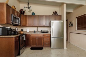 A modern kitchen with wooden cabinets, stainless steel appliances, and a black countertop.