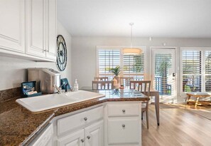 A kitchen with a granite countertop, white cabinets, a stainless steel sink, and a dining area with a table and chairs. - Waterfront Getaway with Deck & Boat Slip (Hot Springs)