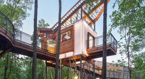 A treehouse with a wooden exterior, metal railings, and a staircase leading up to it. - Waterfront Getaway with Deck & Boat Slip (Hot Springs)