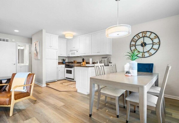 A modern kitchen with white cabinets, a dining table, and a clock on the wall. - Waterfront Getaway with Deck & Boat Slip (Hot Springs)