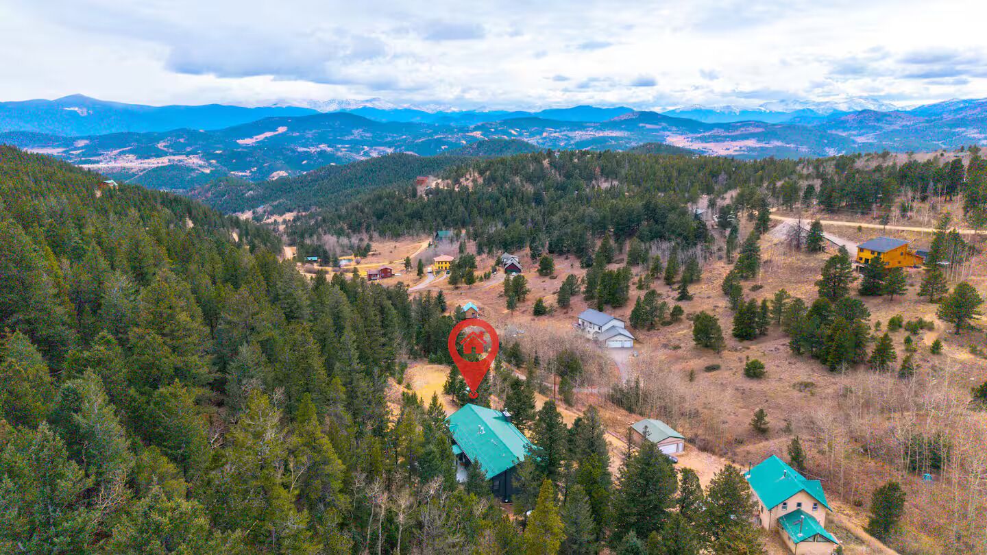 Paisaje montañoso con casas dispersas y un marcador rojo destacado.