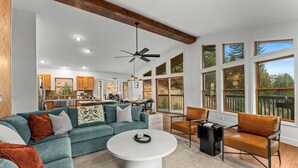 A spacious living room with a large sofa, a coffee table, and a dining area in the background. - Mountain View Retreat - Game Room + 2 Living Areas (Black Hawk)