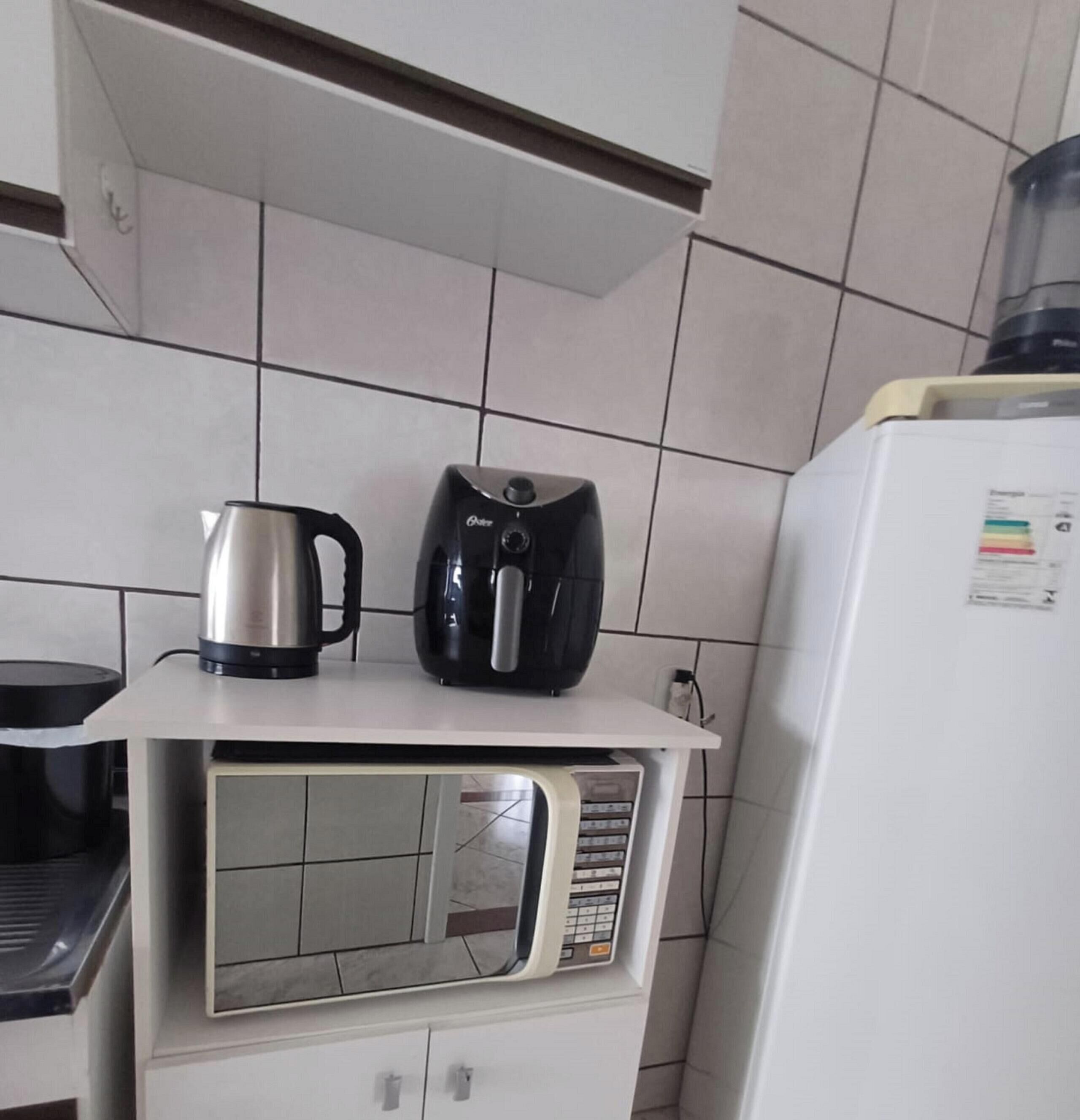 A kitchen with a microwave, a coffee maker, and a refrigerator.
