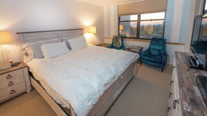 Habitación de hotel con una cama grande, televisión, una silla y ventana con vistas.