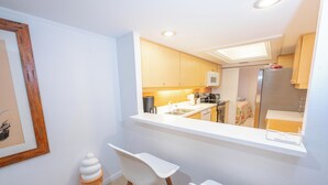 Una cocina compacta con encimera blanca, armarios de madera y un microondas integrado.