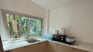 A compact kitchen with a window, a sink, a microwave, and a toaster. - Lovely 1-bedroom private bungalows at riverside resort with AC and full kitchen. (ตำบล เกาะลันตาใหญ่)