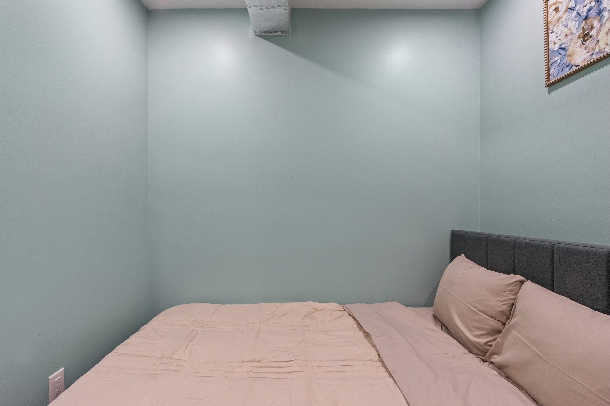 A bedroom with a single bed, light blue walls, and a plain ceiling.