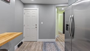 A modern kitchen with grey walls, a white door, a stainless steel refrigerator, and a wooden countertop. - Spacious Home In Troy (Troy)