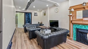 A modern living room with a sectional sofa, a fireplace, and a television. - Spacious Home In Troy (Troy)