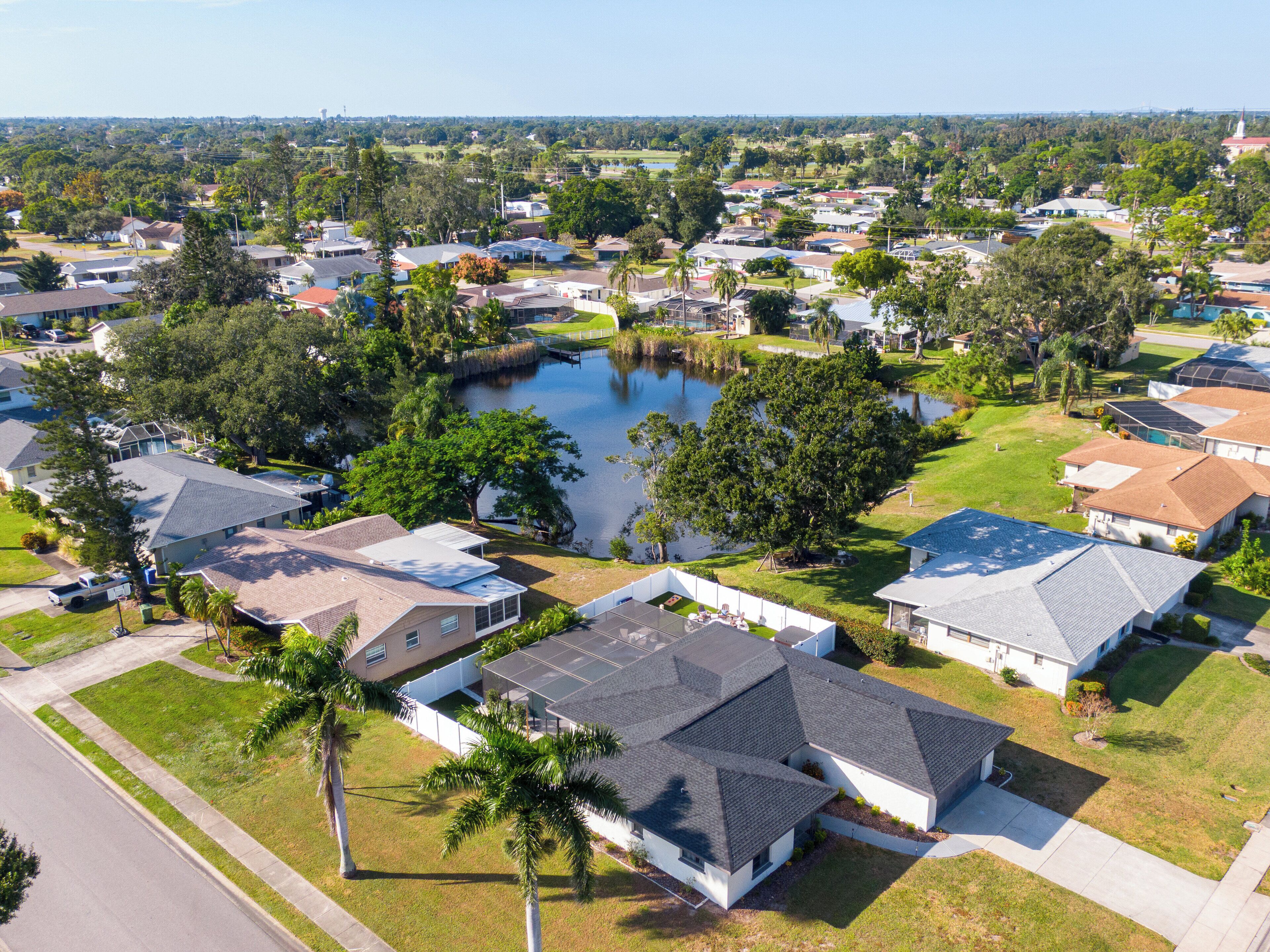 Vue aérienne d’un quartier résidentiel avec des maisons, un lac et la végétation environnante.