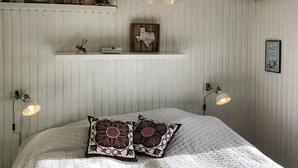 Ein Schlafzimmer mit einem Bett, zwei Wandlampen, einer Ablage mit Dekoration und einer gerahmten Karte an der Wand.