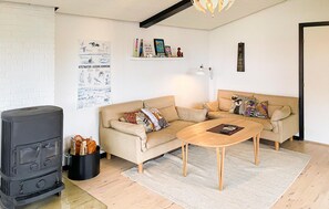 A cozy living room with a sofa set, a wooden coffee table, a black stove, and a wall with a poster. - Gorgeous home in Assens with WiFi (Assens)