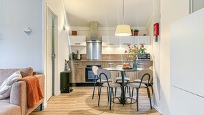 Une cuisine moderne avec un coin repas, un plancher en bois et une petite table avec des chaises.
