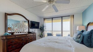 Une chambre avec un grand lit, une commode, une télévision et un balcon avec vue.