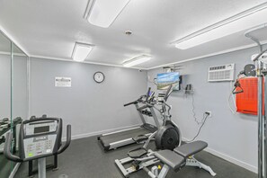 Ein Fitnessraum mit Laufbändern, Crosstrainern und einer Trainingsbank.