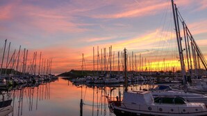 A marina with multiple boats docked at calm waters during sunset.