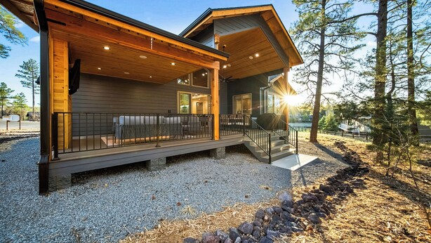 A modern cabin with a covered deck, a stone pathway, and a view of the surrounding forest. - Lake-View Gem w/ Outdoor Entertainment in Show Low (Show Low)