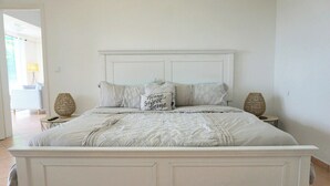 Un lit à baldaquin blanc, doté d’une couvre-lit matelassé et de deux coussins décoratifs.